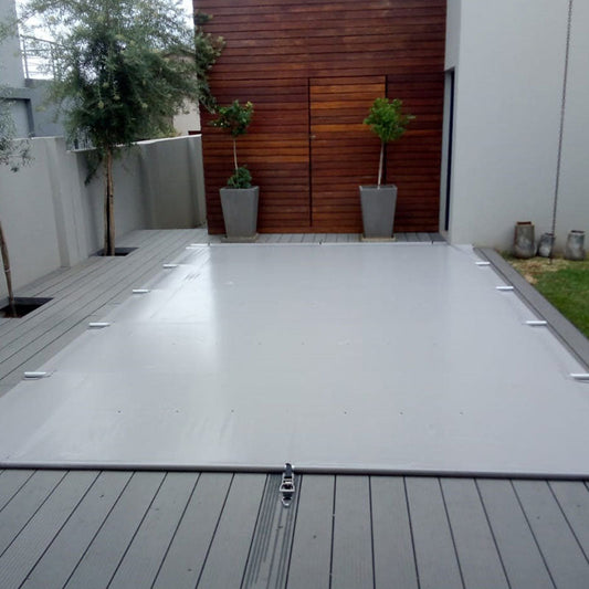 Use this image alt text:  PVC solid pool cover with pole support installed over a swimming pool for improved safety, reduced evaporation and cleaner pool water